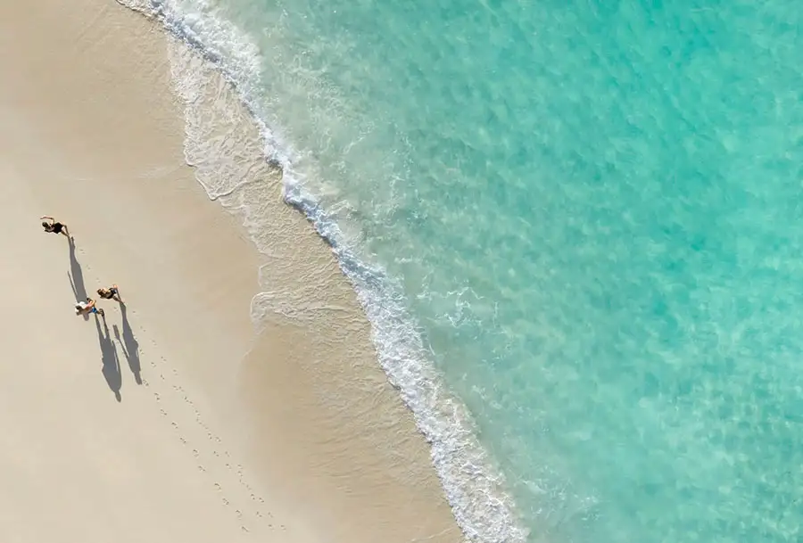 Aerial view of two people walking along the shoreline at Beaches Exuma
