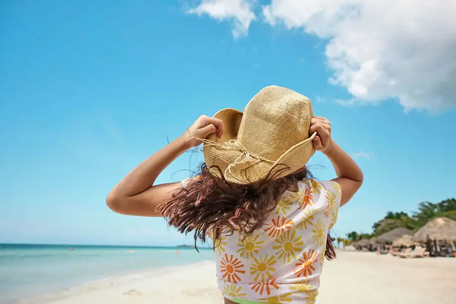 Girl in a sunhat walking along the beach at Beaches Exuma