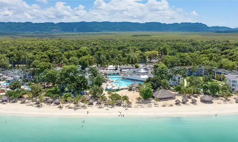 Aerial view of Beaches Negril resort with mountains behind the beachfront
