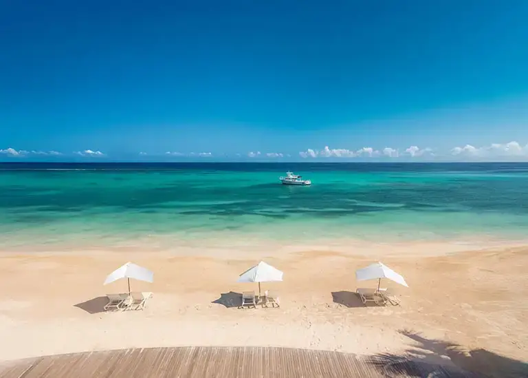 Aerial drone view of the beach lined with umbrellas at Sandals Dunn's River Resort