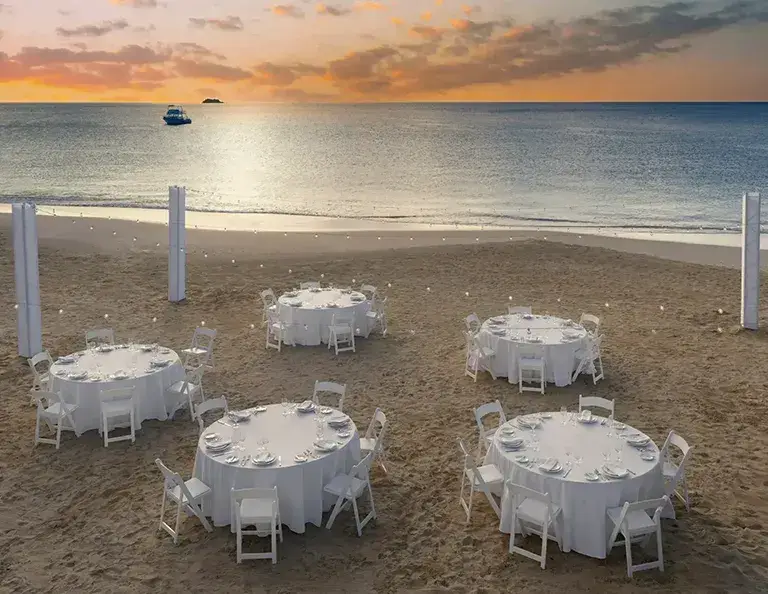 Beach wedding reception tables at sunset at Sandals Grande Antigua