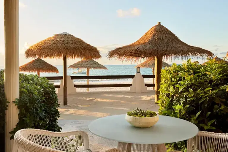 Oceanfront patio with thatched umbrellas at Sandals Grande Antigua