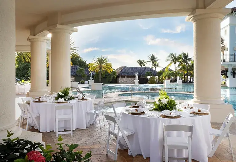 Poolside dining tables under arches overlooking the pool at Sandals Grande Antigua