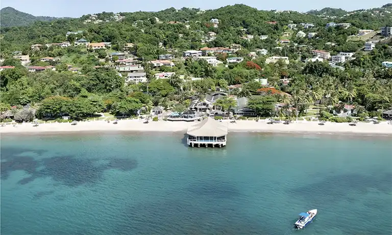 Aerial view of Sandals Halcyon Beach resort cove with pier restaurant