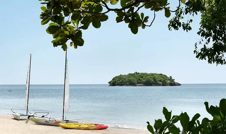 Beach with kayaks and island view at Sandals Halcyon Beach