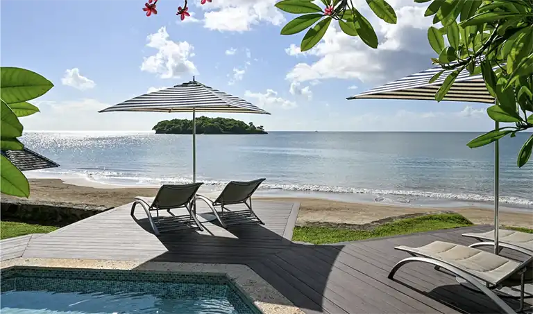 Beachfront pool deck with lounge chairs at Sandals Halcyon Beach