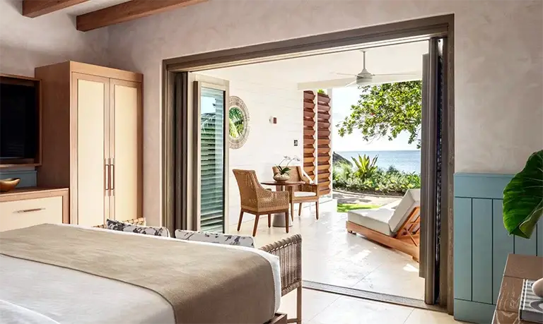 Bedroom with patio doors opening to ocean view at Sandals Halcyon Beach