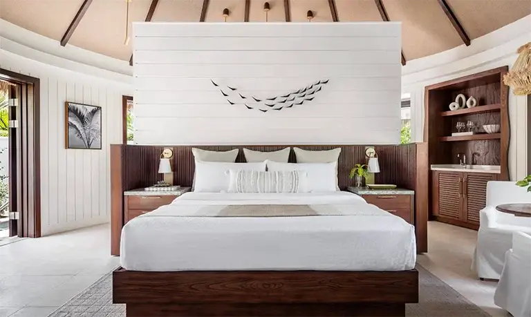 Bedroom with wood bed frame and bird artwork at Sandals Halcyon Beach