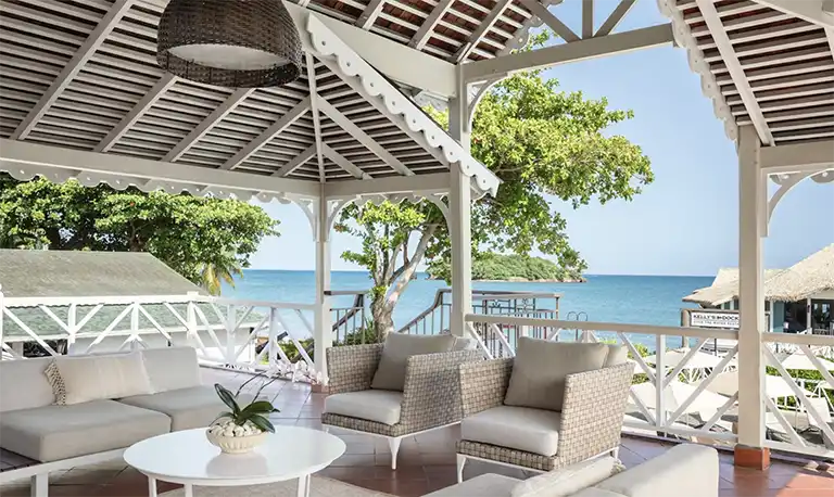 Covered veranda lounge seating overlooking the ocean at Sandals Halcyon Beach