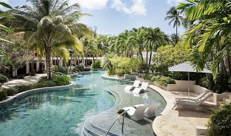Lush resort pool surrounded by palm trees at Sandals Halcyon Beach