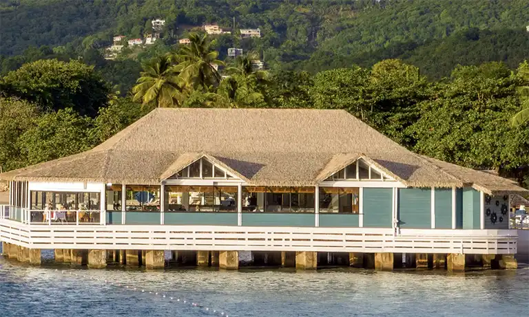 Overwater pier restaurant at Sandals Halcyon Beach at dusk