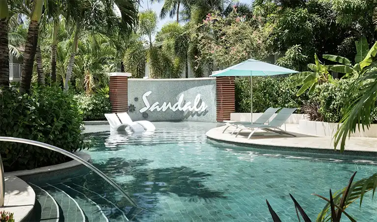 Resort pool with Sandals signage and palm trees at Sandals Halcyon Beach