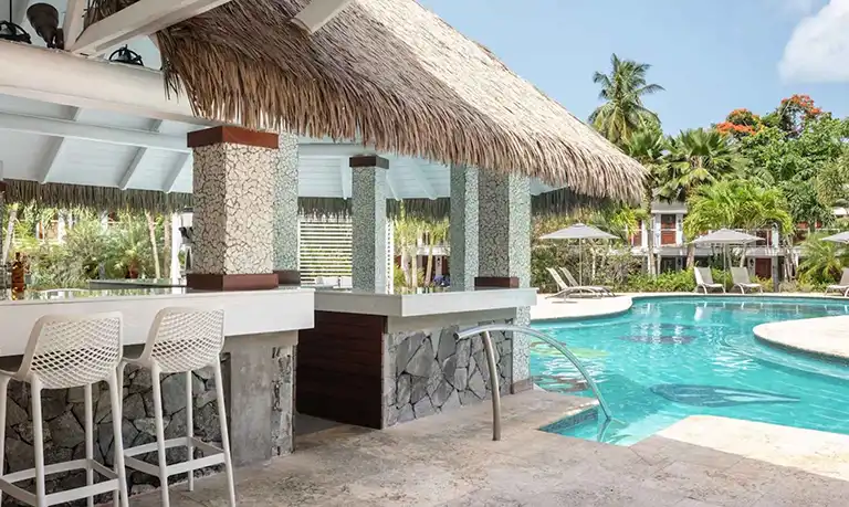 Thatched-roof swim-up pool bar at Sandals Halcyon Beach