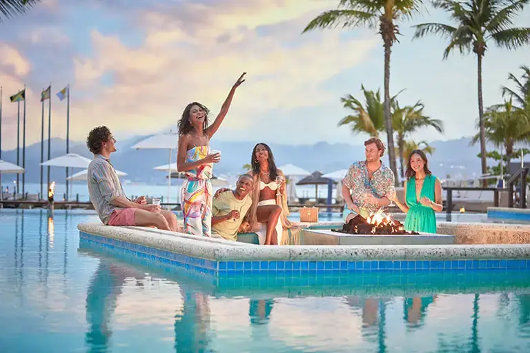 Guests gathered by the pool fire pit at Sandals La Source Grenada