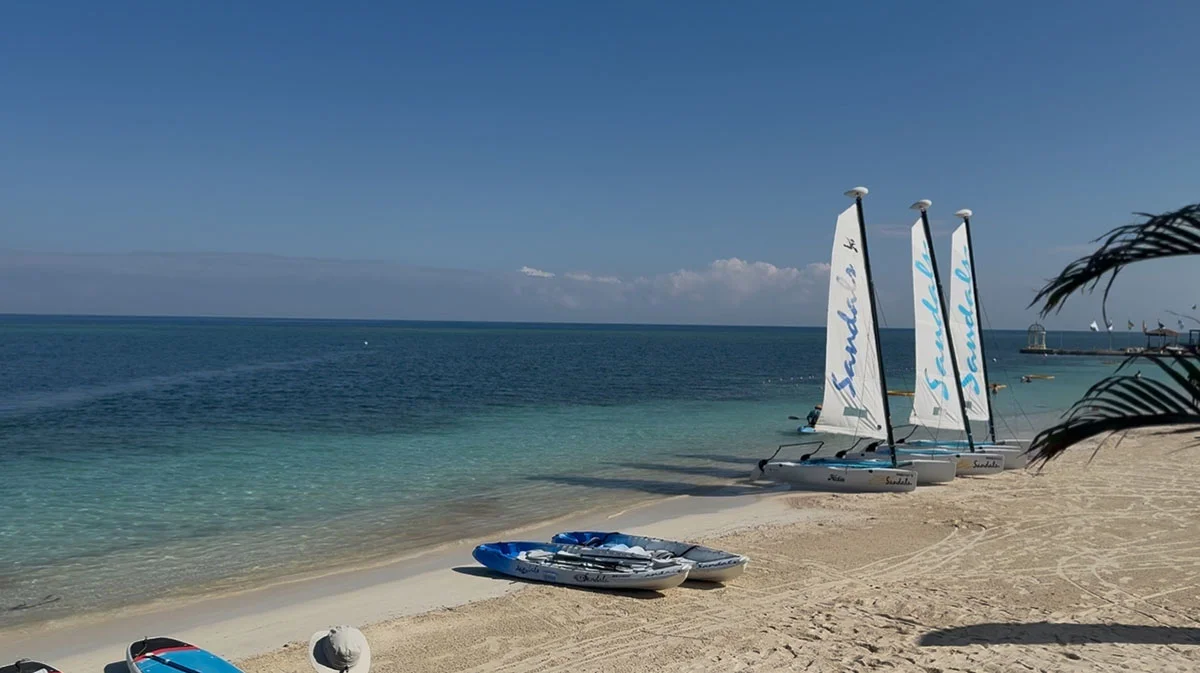 Sailboats and water sports equipment on the beach at Sandals Montego Bay