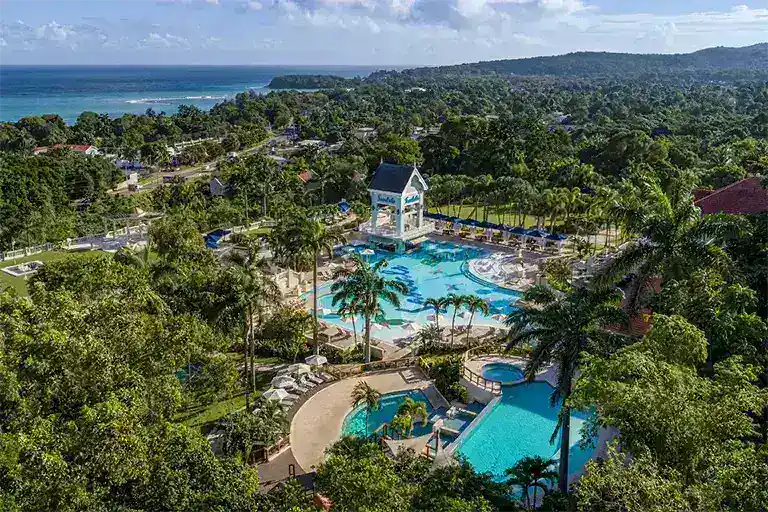 Aerial view of Sandals Ochi Rios resort pool complex with white gazebo and ocean view