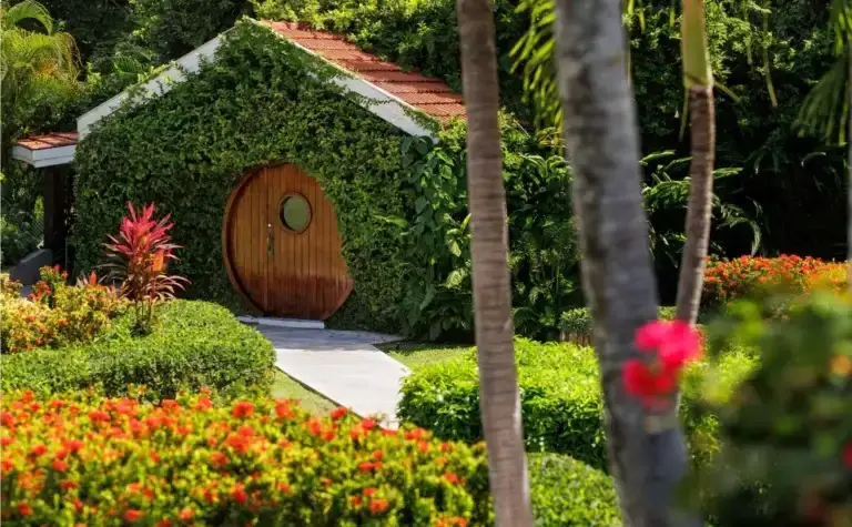 Whimsical garden cottage with round door surrounded by tropical flowers at Sandals Ochi Rios