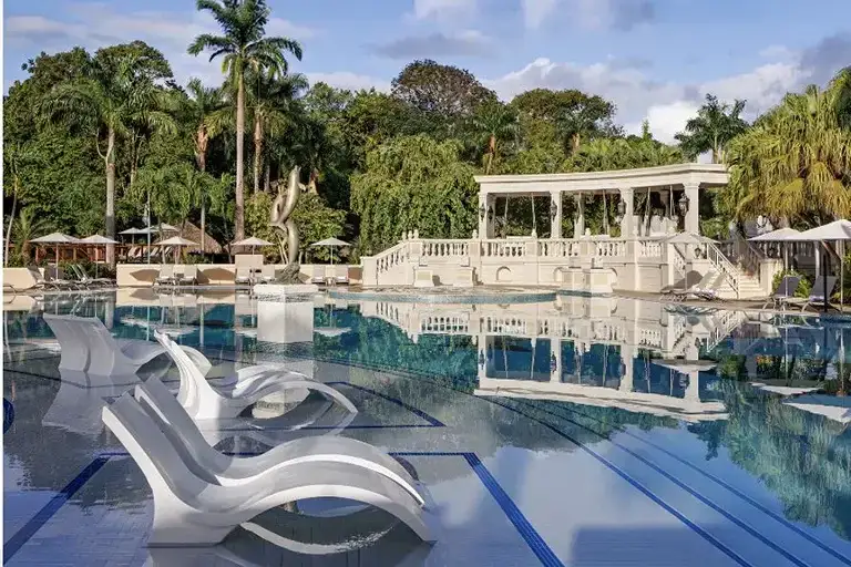 Garden pool with lounge chairs and gazebo bridge at Sandals Ochi Beach Resort