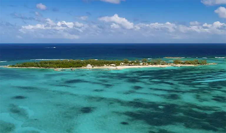 Aerial view of a small island surrounded by turquoise reef near Sandals Royal Bahamian