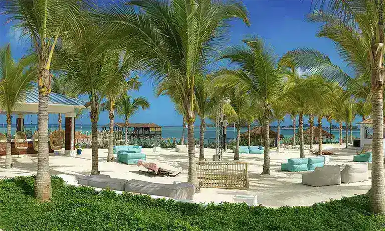 Beachfront daybeds shaded by palm trees at Sandals Royal Bahamian