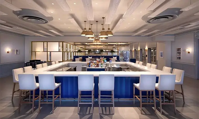 Modern blue and white bar lounge with chandeliers at Sandals Royal Bahamian