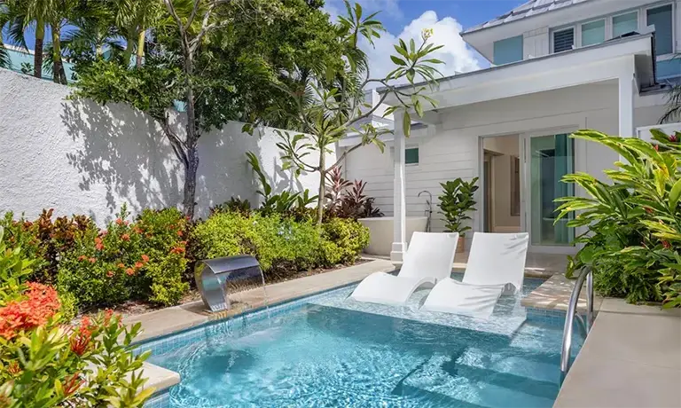 Outdoor plunge pool with lounge chairs beside a private villa at Sandals Royal Bahamian