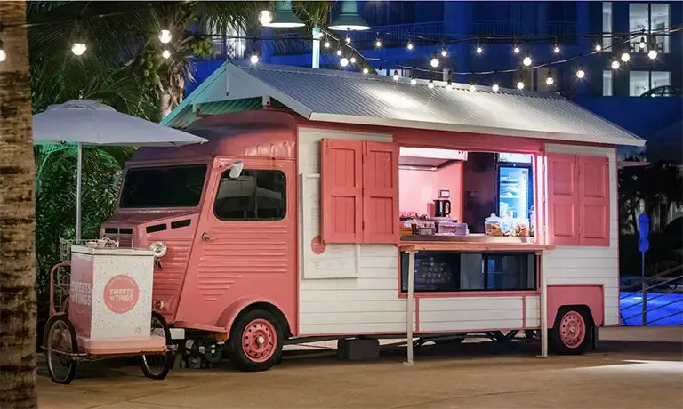 Pink vintage food truck cafe lit up at night at Sandals Royal Bahamian