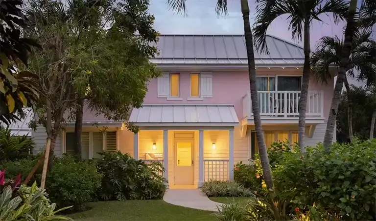 Pink cottage-style villa exterior at dusk at Sandals Royal Bahamian