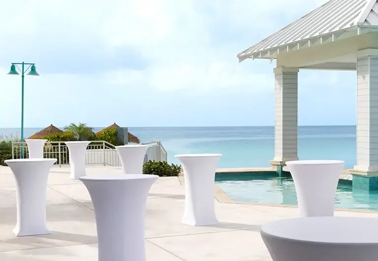 Cocktail-style high-top tables on the pool deck overlooking the ocean at Sandals Royal Bahamian