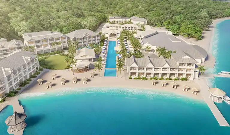 Aerial view of Sandals Royal Caribbean resort with pier, pools, and turquoise ocean