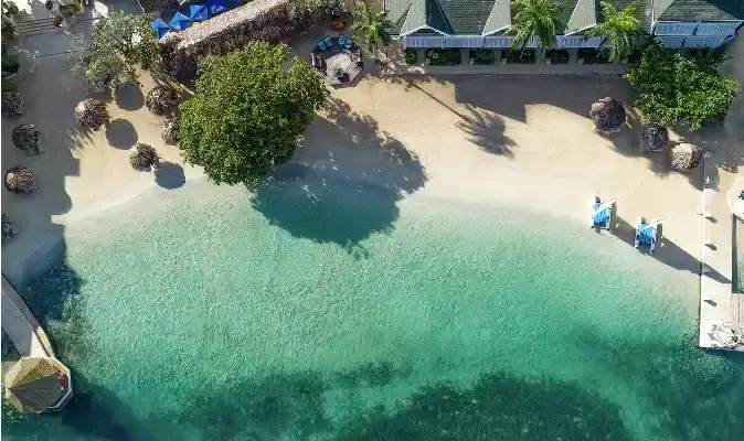 Aerial view of a sandy beach cove with turquoise water at Sandals Royal Caribbean