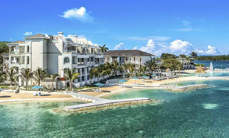Aerial view of a beachfront resort building and pier at Sandals Royal Caribbean