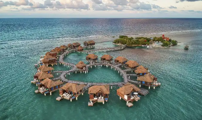 Aerial daytime view of the heart-shaped private island of overwater villas at Sandals Royal Caribbean