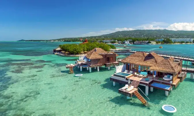 Aerial view of overwater bungalows with guests relaxing at Sandals Royal Caribbean