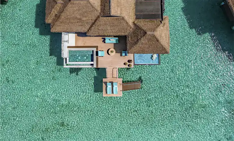 Aerial view of overwater villa rooftops surrounded by turquoise water at Sandals Royal Caribbean