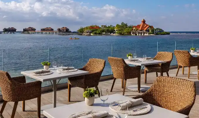 Oceanfront pier dining tables with a gazebo island in the background at Sandals Royal Caribbean