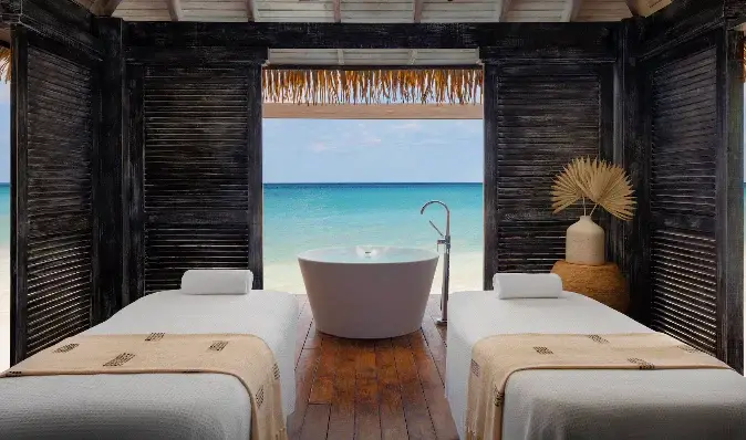 Overwater spa treatment room with soaking tub and ocean view at Sandals Royal Caribbean
