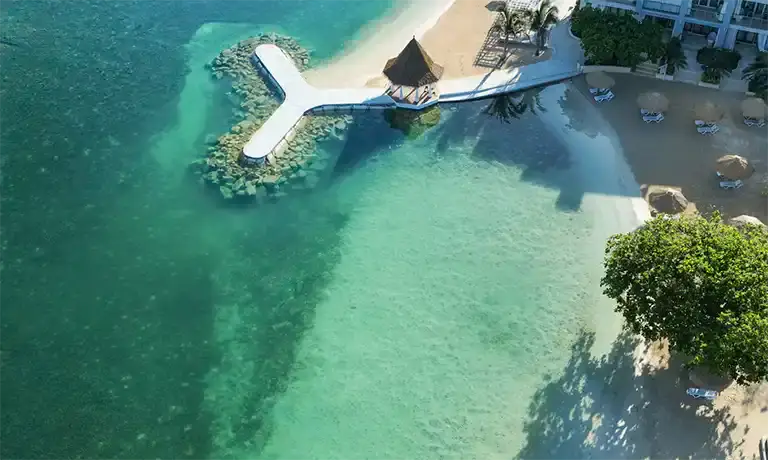 Aerial view of an overwater swim platform surrounded by turquoise water at Sandals Royal Caribbean