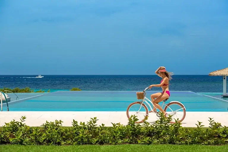 Woman riding a bike beside the main pool at Sandals Royal Curacao