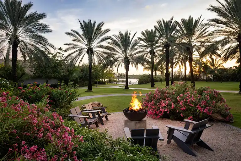 Garden fire pit surrounded by palm trees and flowers at Sandals Royal Curacao