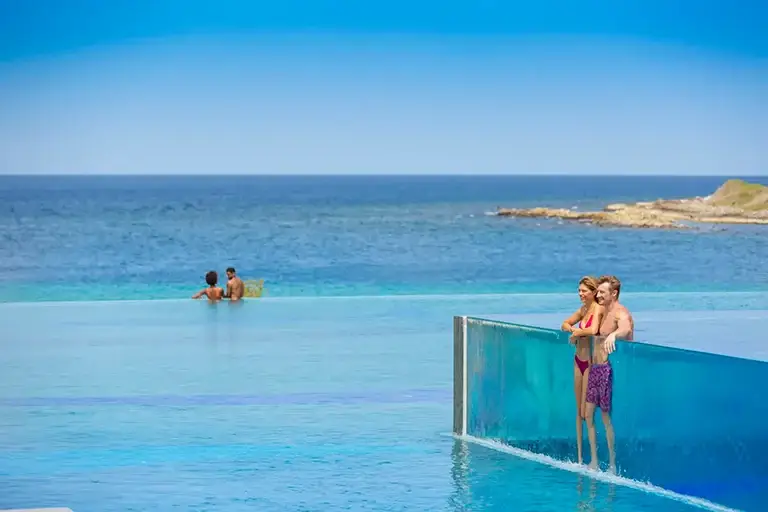 Couples relaxing at the infinity pool overlooking the ocean at Sandals Royal Curacao