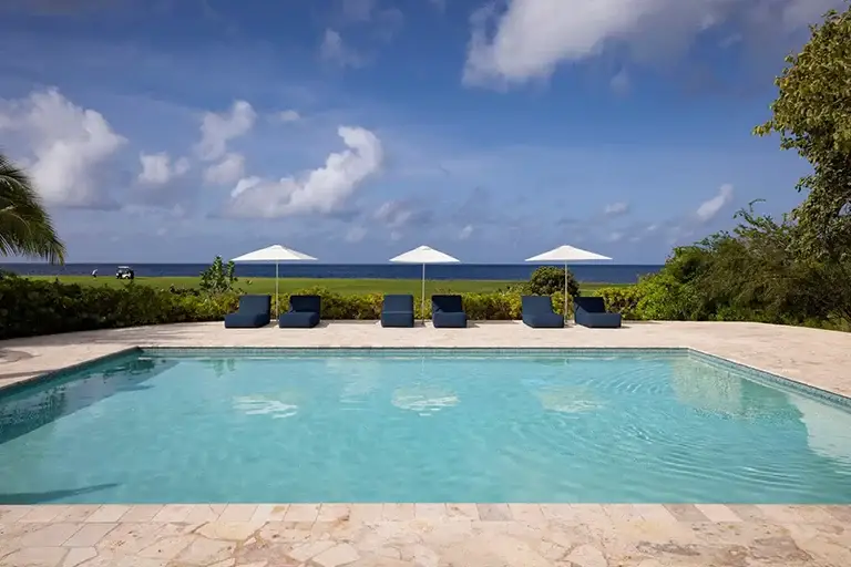 MeleMele pool with lounge chairs and ocean view at Sandals Royal Curacao
