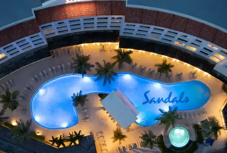 Aerial night view of the pool area with illuminated Sandals sign