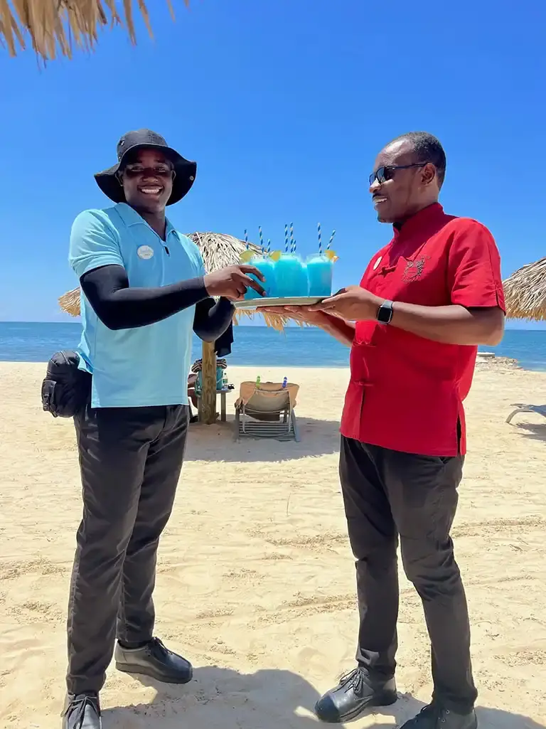 Resort staff presenting welcome drinks on the beach at Sandals South Coast
