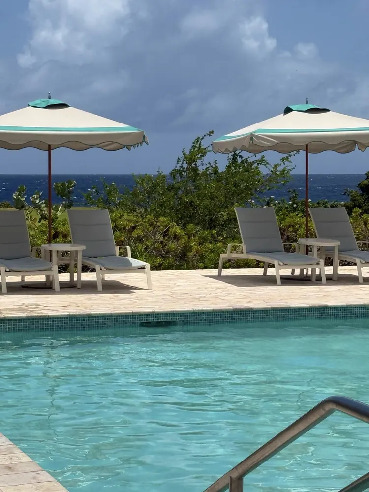 Pool deck with striped umbrellas and loungers at Sandals Royal Curaçao