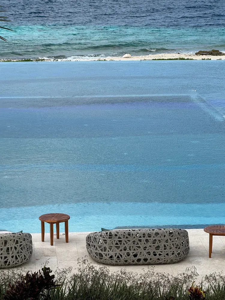 Infinity pool edge blending into the turquoise sea at Sandals Royal Curaçao